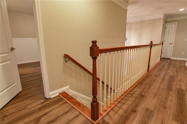 stairway with wood-type flooring and ornamental molding