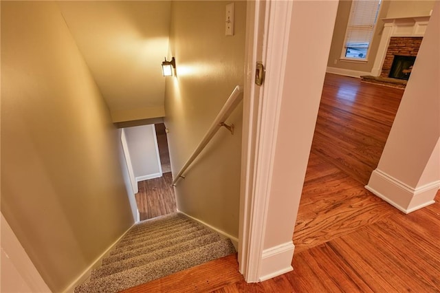 stairway featuring hardwood / wood-style flooring and a fireplace