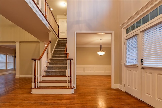 foyer entrance featuring crown molding, a towering ceiling, and hardwood / wood-style flooring