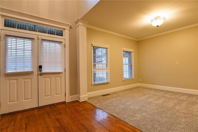 foyer with crown molding, dark hardwood / wood-style flooring, and decorative columns