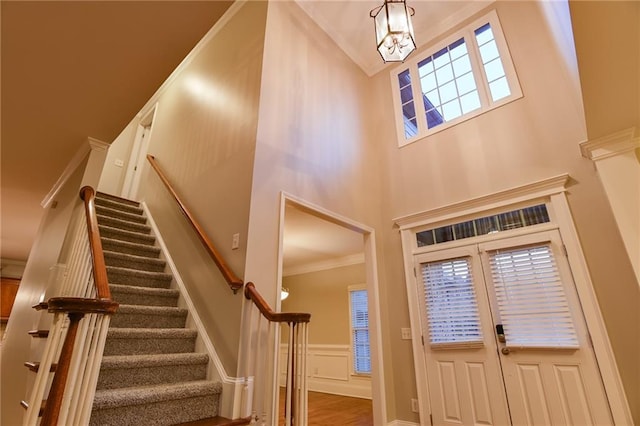 foyer entrance featuring a towering ceiling, ornamental molding, and hardwood / wood-style floors