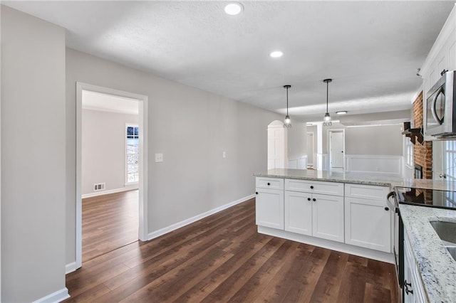 kitchen featuring visible vents, stainless steel microwave, dark wood-type flooring, a peninsula, and white cabinetry