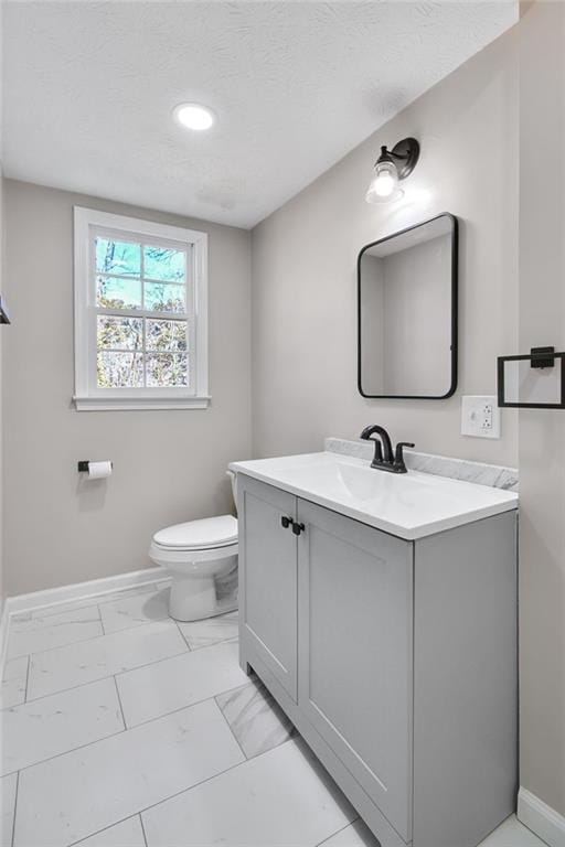 bathroom featuring marble finish floor, toilet, vanity, a textured ceiling, and baseboards