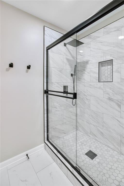 full bathroom with marble finish floor, baseboards, and a stall shower