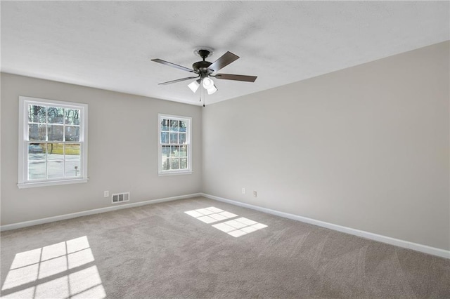 unfurnished room featuring carpet, baseboards, visible vents, and ceiling fan