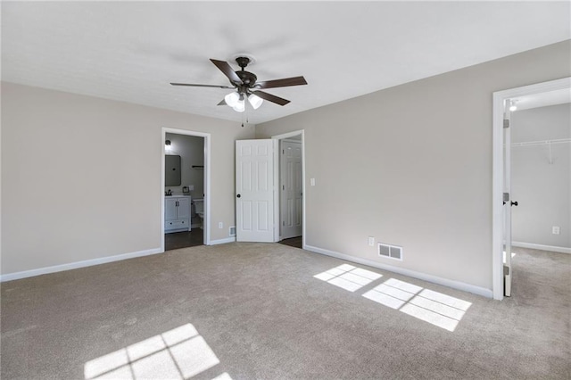 unfurnished bedroom featuring carpet floors, a closet, a spacious closet, and baseboards