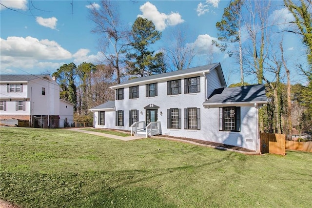 view of front of home with brick siding, fence, and a front lawn