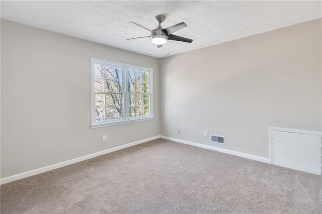 spare room featuring a textured ceiling, carpet flooring, visible vents, and baseboards