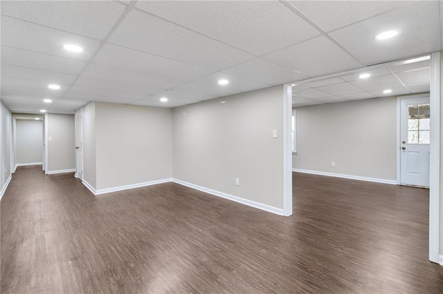 basement featuring recessed lighting, dark wood finished floors, a paneled ceiling, and baseboards