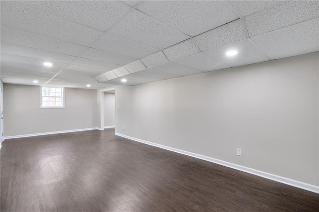 basement featuring dark wood-style floors, recessed lighting, a paneled ceiling, and baseboards