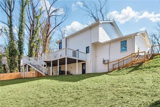 rear view of property with fence, a lawn, a deck, and stairs