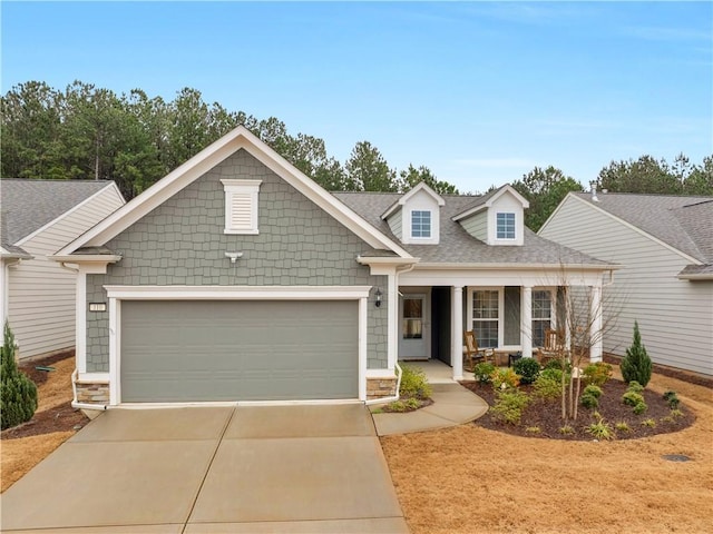 view of front facade featuring driveway, an attached garage, a porch, and roof with shingles