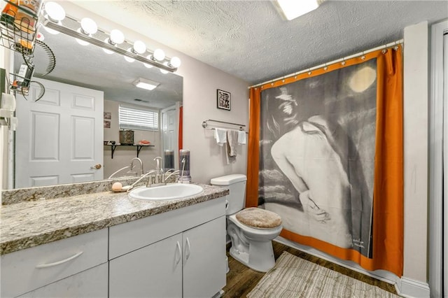 bathroom with a textured ceiling, toilet, wood finished floors, and vanity