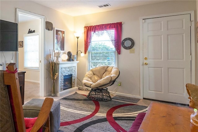 living area with visible vents, plenty of natural light, a stone fireplace, and baseboards