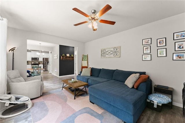 living room featuring light wood finished floors, a ceiling fan, and baseboards