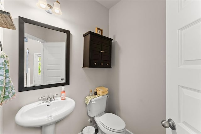 half bathroom featuring a sink, toilet, and baseboards