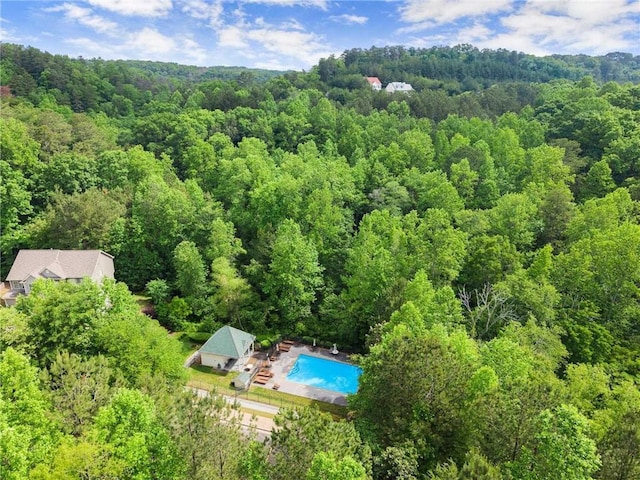 drone / aerial view of a heavily wooded area and a pool