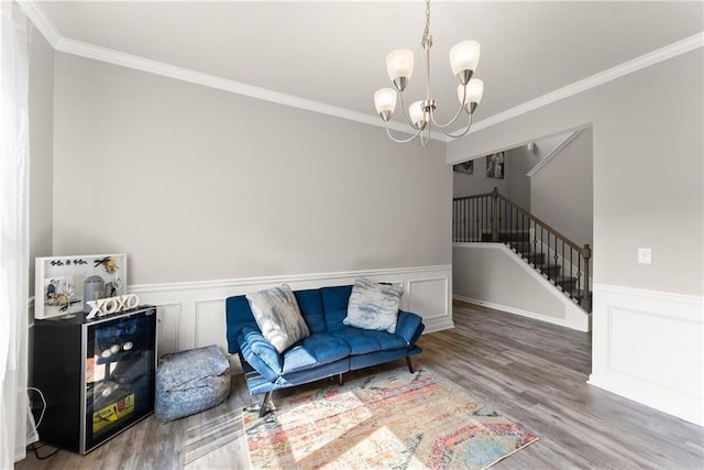 sitting room with a chandelier, crown molding, wainscoting, wood finished floors, and stairs