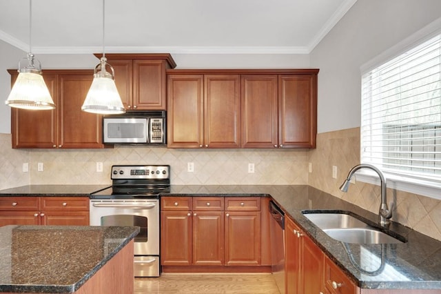 kitchen with appliances with stainless steel finishes, dark stone countertops, a sink, and crown molding