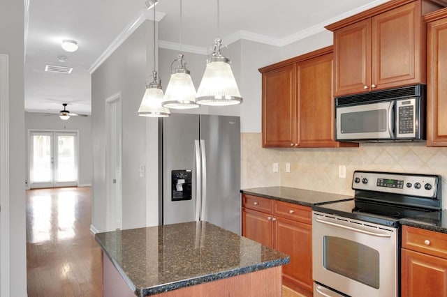 kitchen with crown molding, stainless steel appliances, brown cabinets, and decorative backsplash