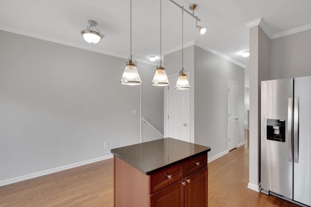 kitchen with baseboards, ornamental molding, light wood-type flooring, dark stone counters, and stainless steel fridge