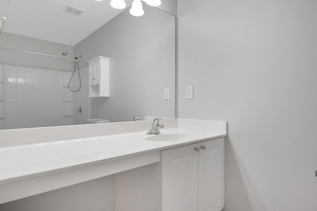 bathroom with visible vents, a shower, and vanity