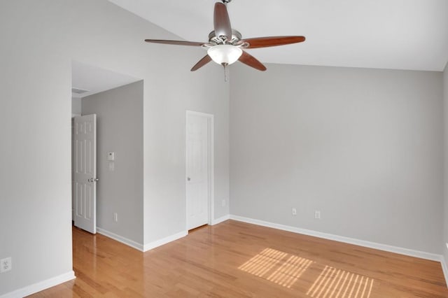 empty room featuring light wood-style floors, baseboards, vaulted ceiling, and a ceiling fan