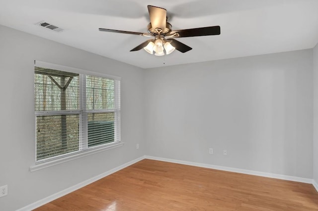 spare room featuring baseboards, a ceiling fan, visible vents, and light wood-style floors