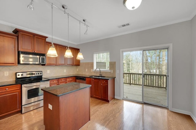 kitchen with light wood-type flooring, appliances with stainless steel finishes, decorative backsplash, and a sink