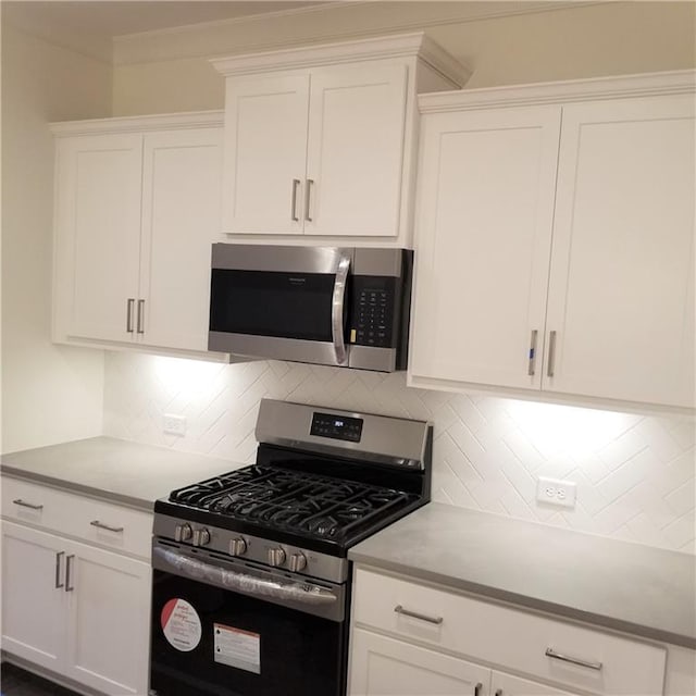 kitchen featuring stainless steel appliances, white cabinets, and backsplash