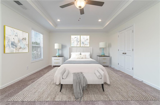 carpeted bedroom with crown molding, a tray ceiling, and ceiling fan