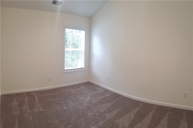 carpeted spare room featuring vaulted ceiling