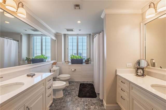 full bath with visible vents, two vanities, a sink, and ornamental molding