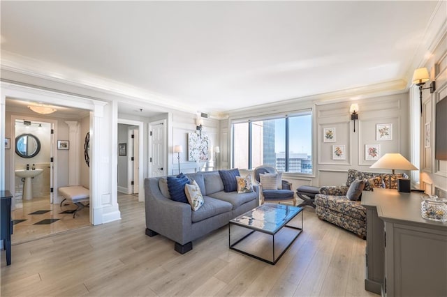 living room with crown molding, visible vents, and light wood-style floors