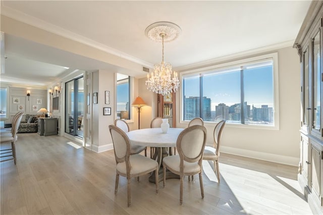 dining space with crown molding, baseboards, light wood-style flooring, and a notable chandelier