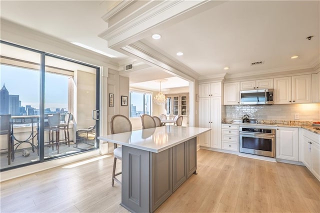 kitchen with visible vents, decorative backsplash, appliances with stainless steel finishes, ornamental molding, and a kitchen breakfast bar