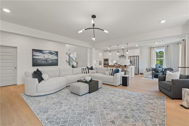 living room with light hardwood / wood-style floors and a notable chandelier