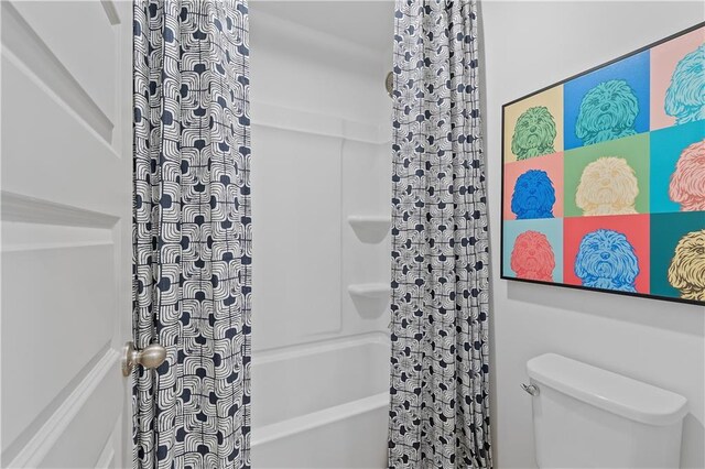 bathroom with shower / bath combination with curtain and toilet