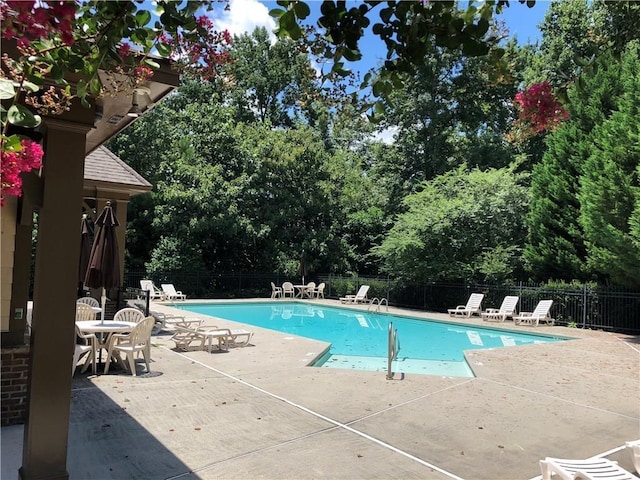 pool with a patio area and fence