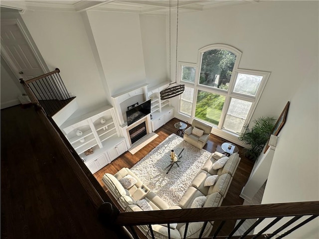 living area featuring a glass covered fireplace, wood finished floors, and crown molding