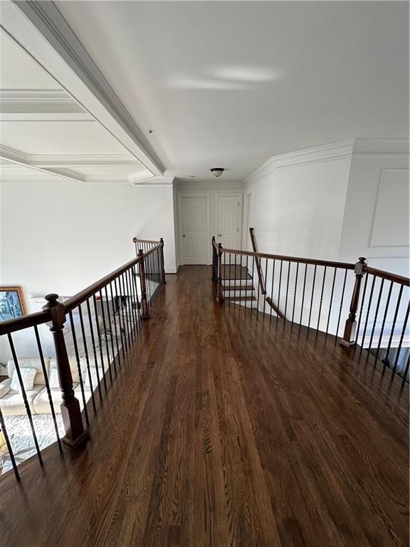 hallway featuring beamed ceiling, an upstairs landing, dark wood-style floors, and ornamental molding