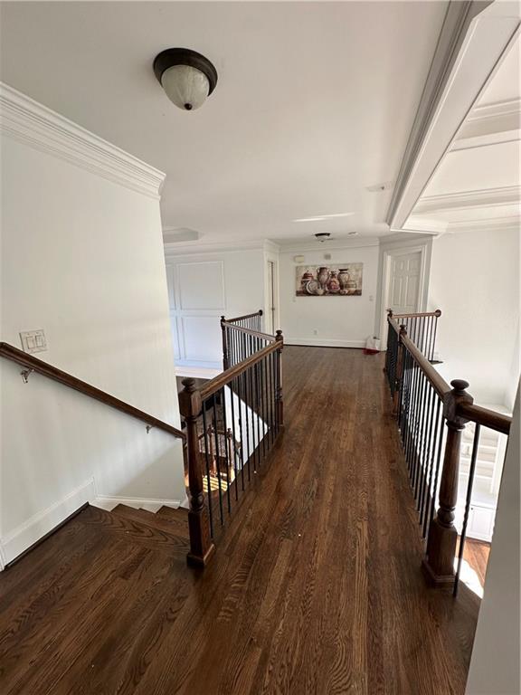 staircase with beam ceiling, crown molding, wood finished floors, and baseboards