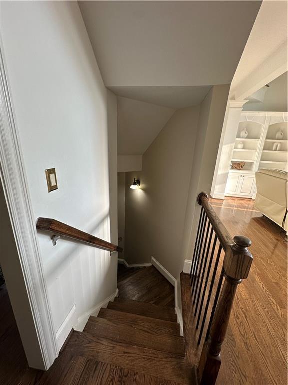 stairway with baseboards, lofted ceiling, and wood finished floors