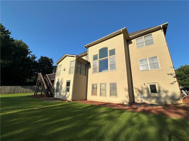 back of property with stairway and a yard