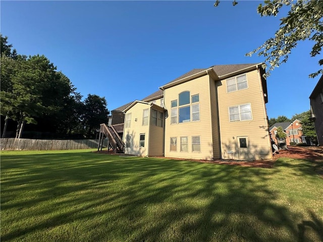 back of property with a lawn, stairs, and fence