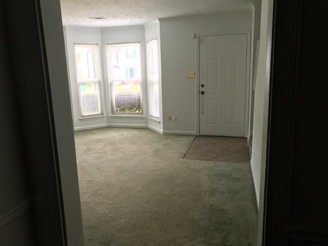 carpeted entryway featuring a textured ceiling