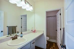 bathroom featuring toilet, vanity, curtained shower, and hardwood / wood-style floors