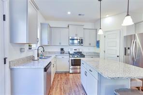 kitchen featuring sink, hanging light fixtures, light wood-type flooring, appliances with stainless steel finishes, and a kitchen breakfast bar