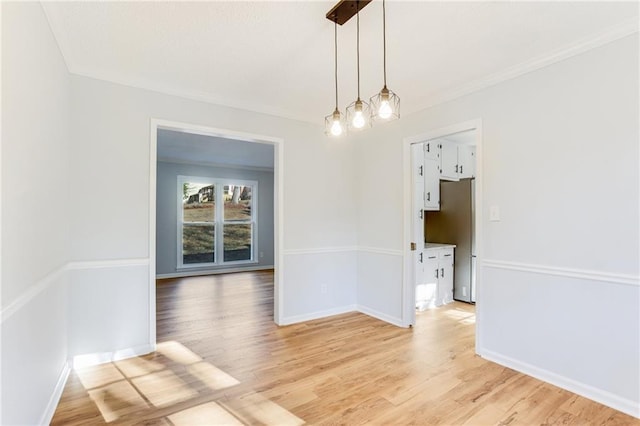 unfurnished dining area featuring ornamental molding and light hardwood / wood-style flooring