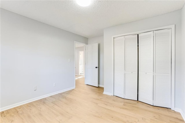 unfurnished bedroom with a textured ceiling, light wood-type flooring, and a closet